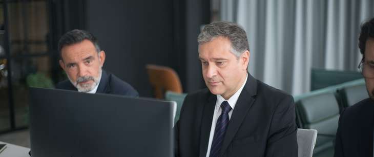 Two business men sitting in front of a computer